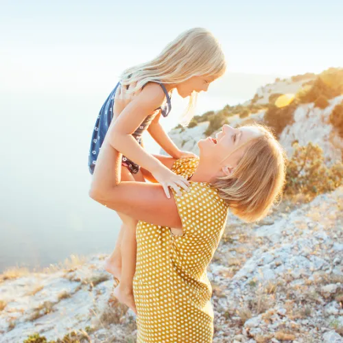 Mom holding little girl up smiling at each other.