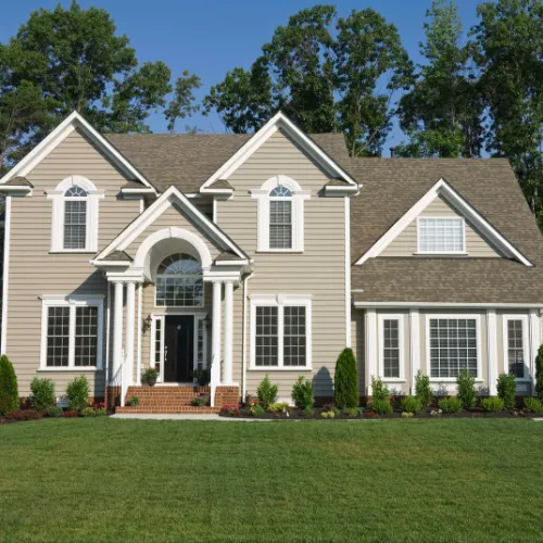 Brown two-story house with large yard.
